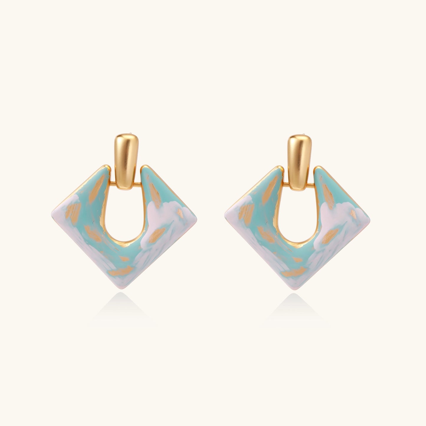 Diamond-shaped gold-plated earrings with pastel marble enamel in turquoise and lavender swirls on beige background