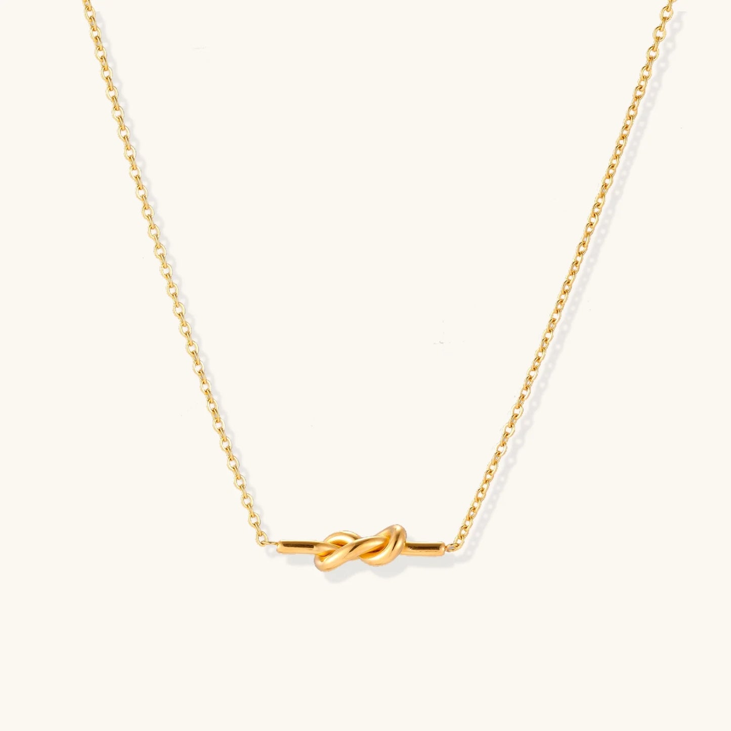 Dainty 18K gold plated necklace with infinity knot pendant on delicate chain against white background