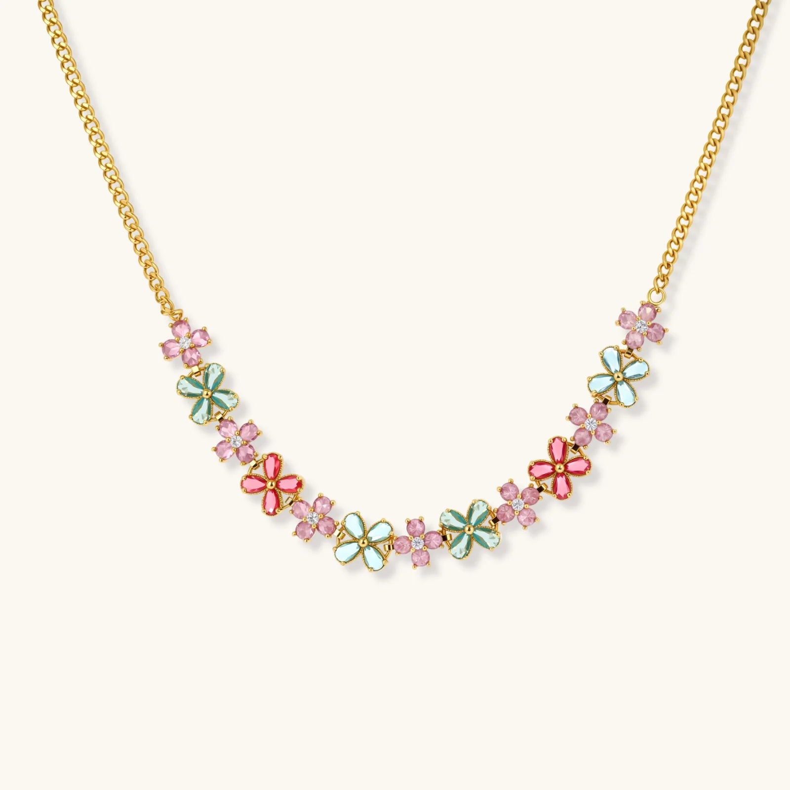 Gold-plated jewelry set with pink, turquoise and red flower-shaped cubic zirconia stones, featuring necklace, earrings and bracelet.