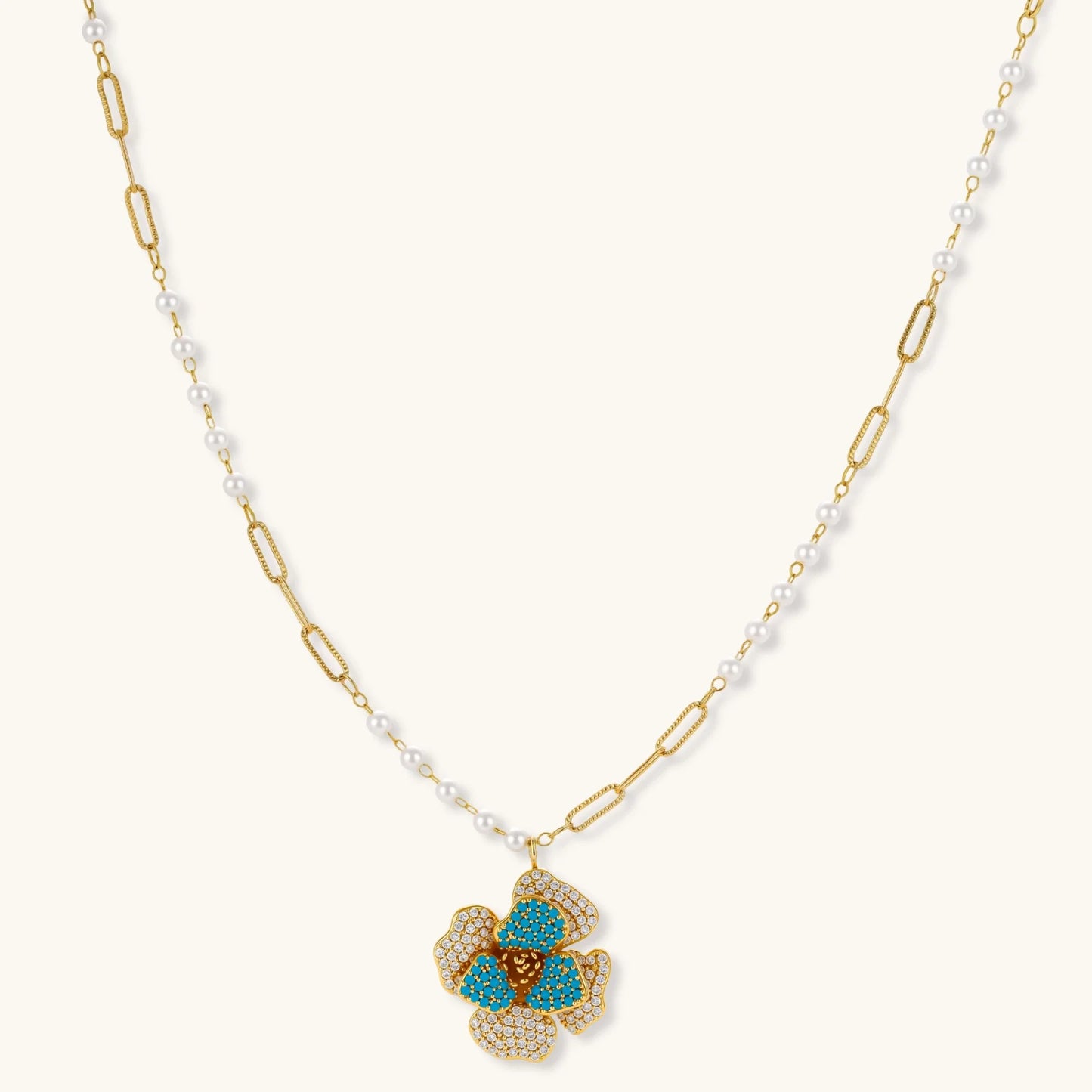 14K gold-plated floral jewelry set with blue cubic zirconia centers and pearl chain details on white background.