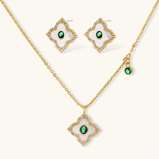 Gold-plated quatrefoil pendant and earrings with white enamel, emerald CZ center stones, and crystal borders on white background.